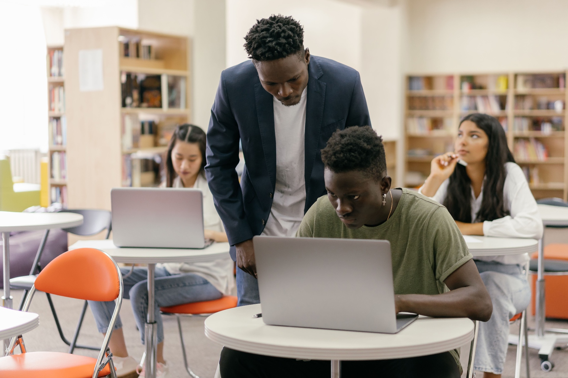 Mentor helping a student on a laptop in a study space